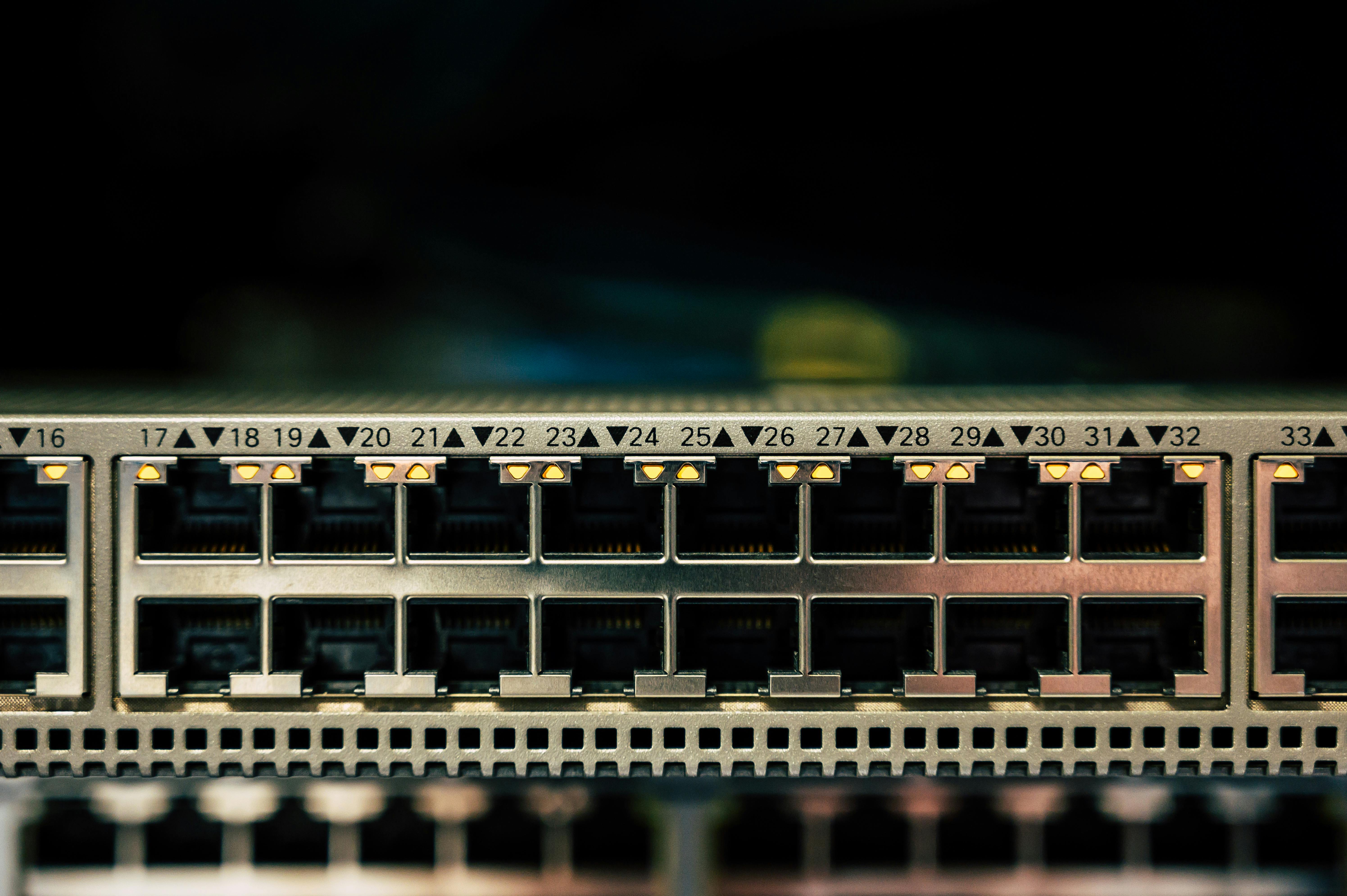 Close-up of an Ethernet switch showing ports numbered 16 to 33, with several LED indicators lit above the ports, indicating active network connections.